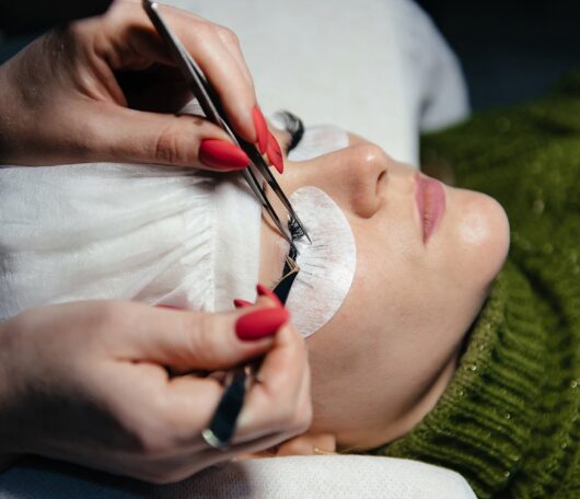 eyelash-extension-process-closeup-portrait-young-girl-woman-with-long-thick-eyelashes-eyes-closed-hand-cosmetologist-adding-more-eyelashes-her